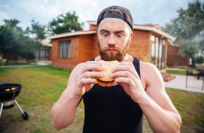 Homme ahuri qui tient un burger